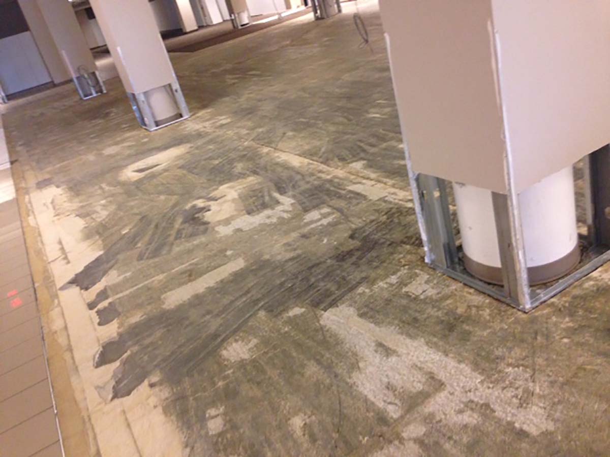 Commercial floor stripped of tile with columns wrapped in plastic during restoration