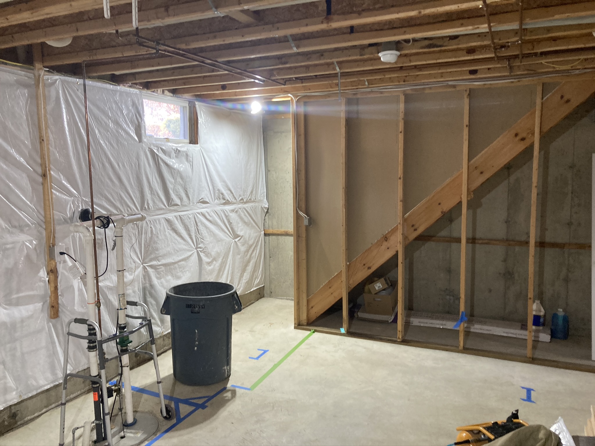 Basement during rebuild with plastic containment sheeting and new framing