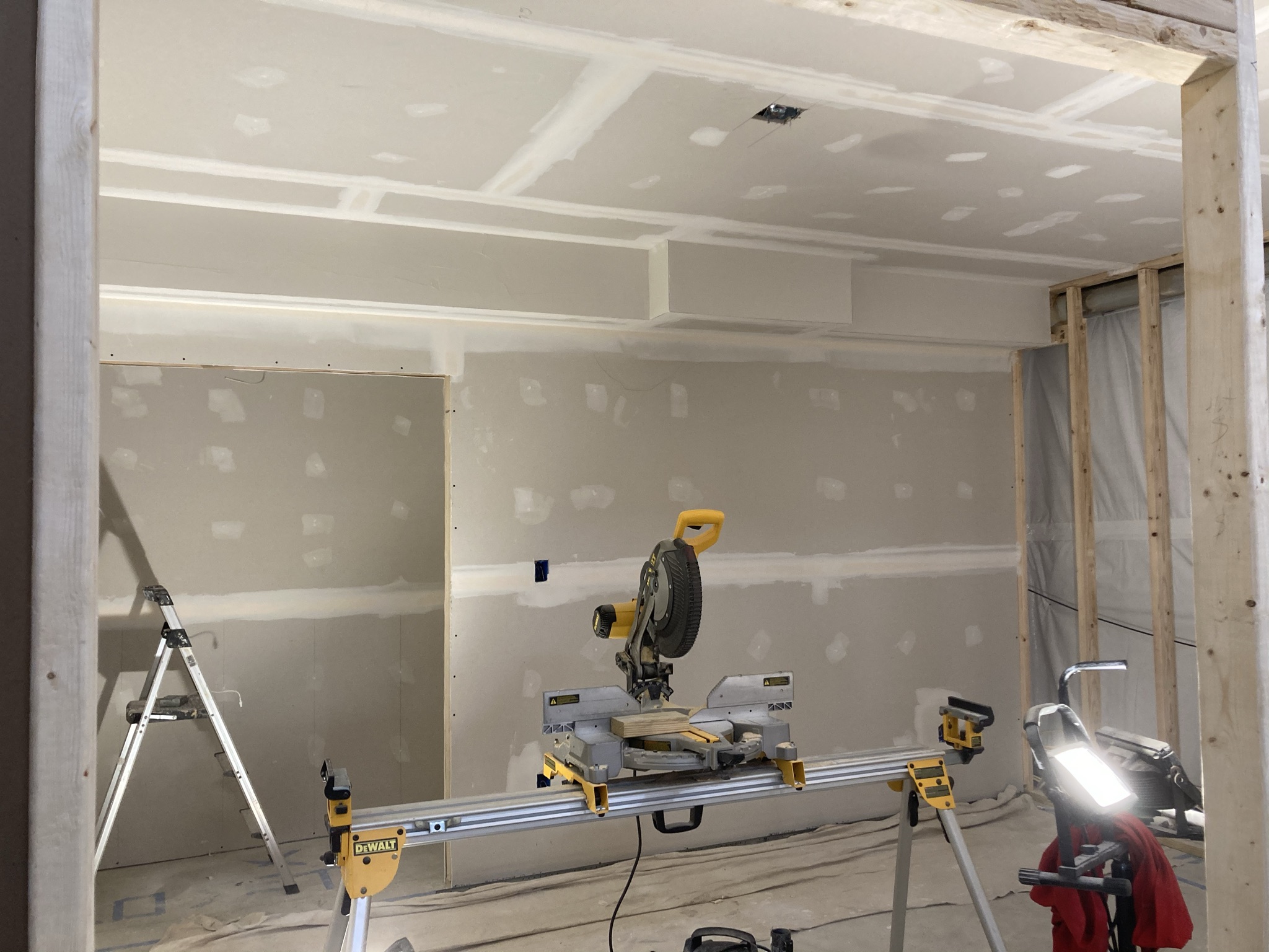 Basement with drywall hung and a miter saw set up during finishing