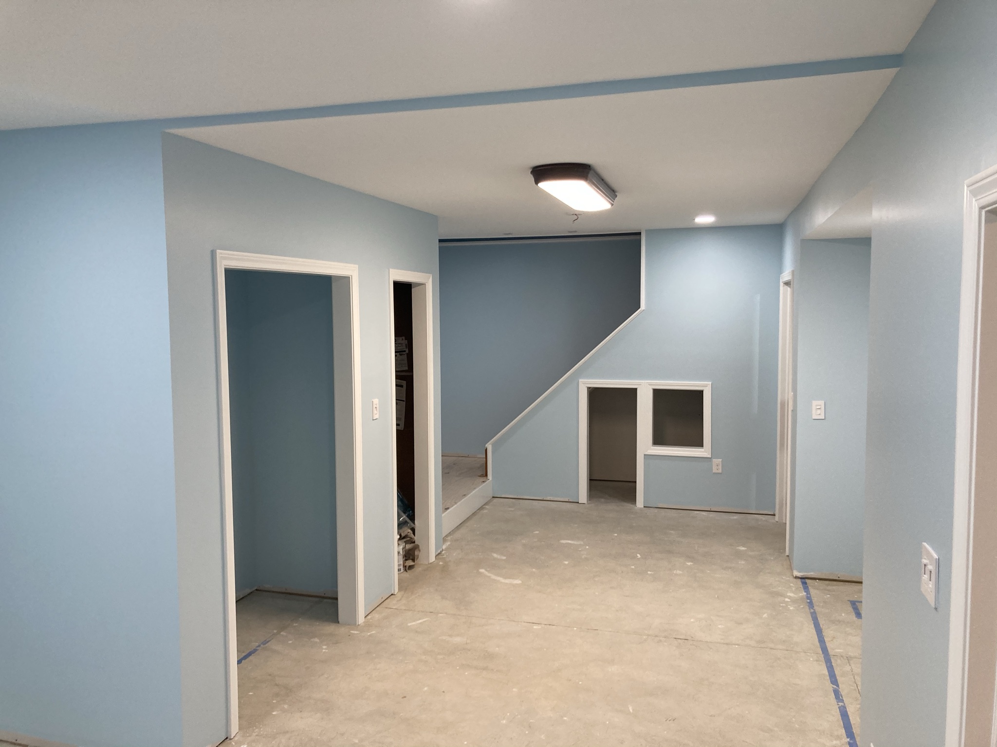 Finished basement painted light blue with recessed lighting