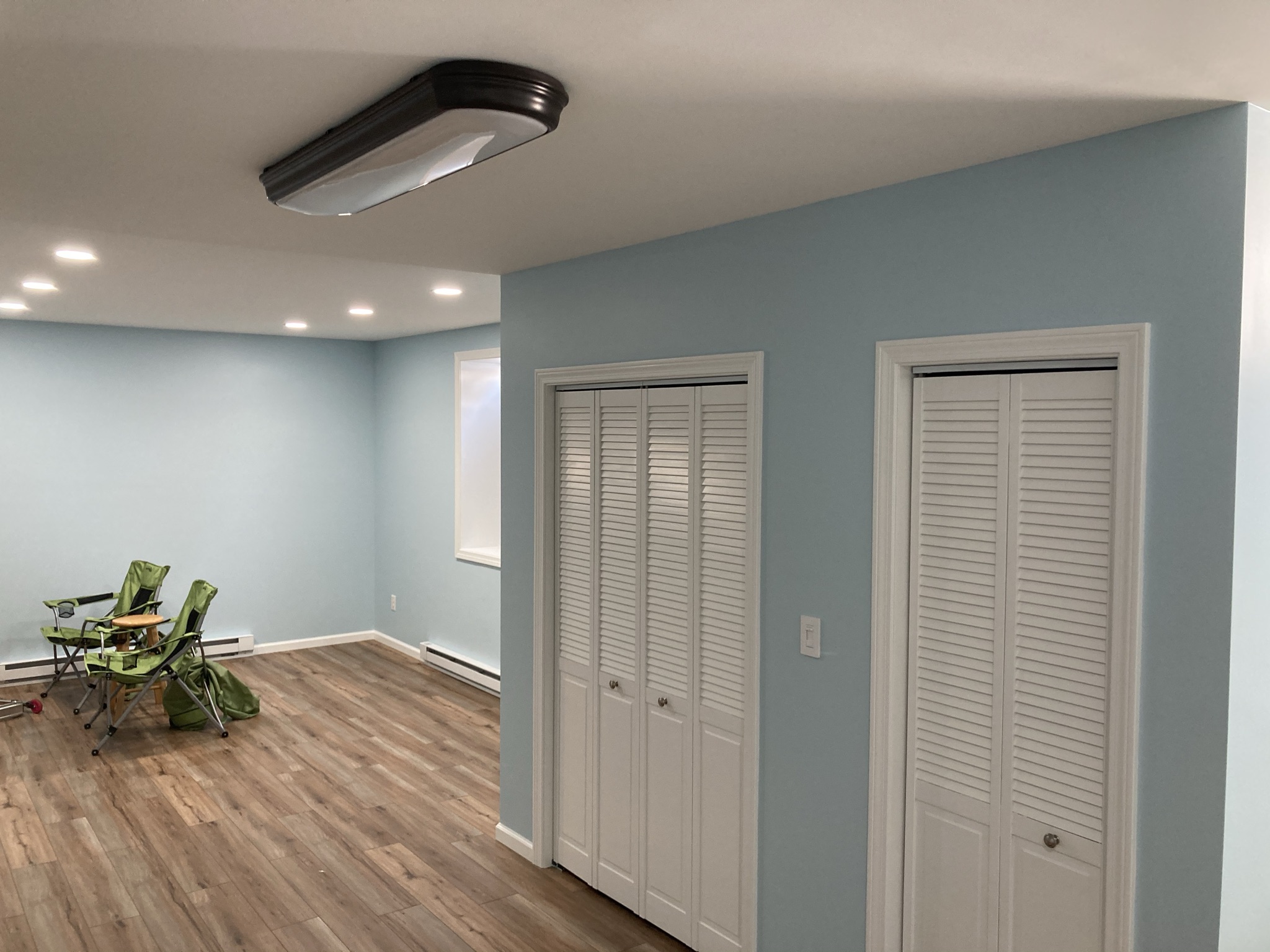 Finished basement room with blue walls, new flooring, and closet doors