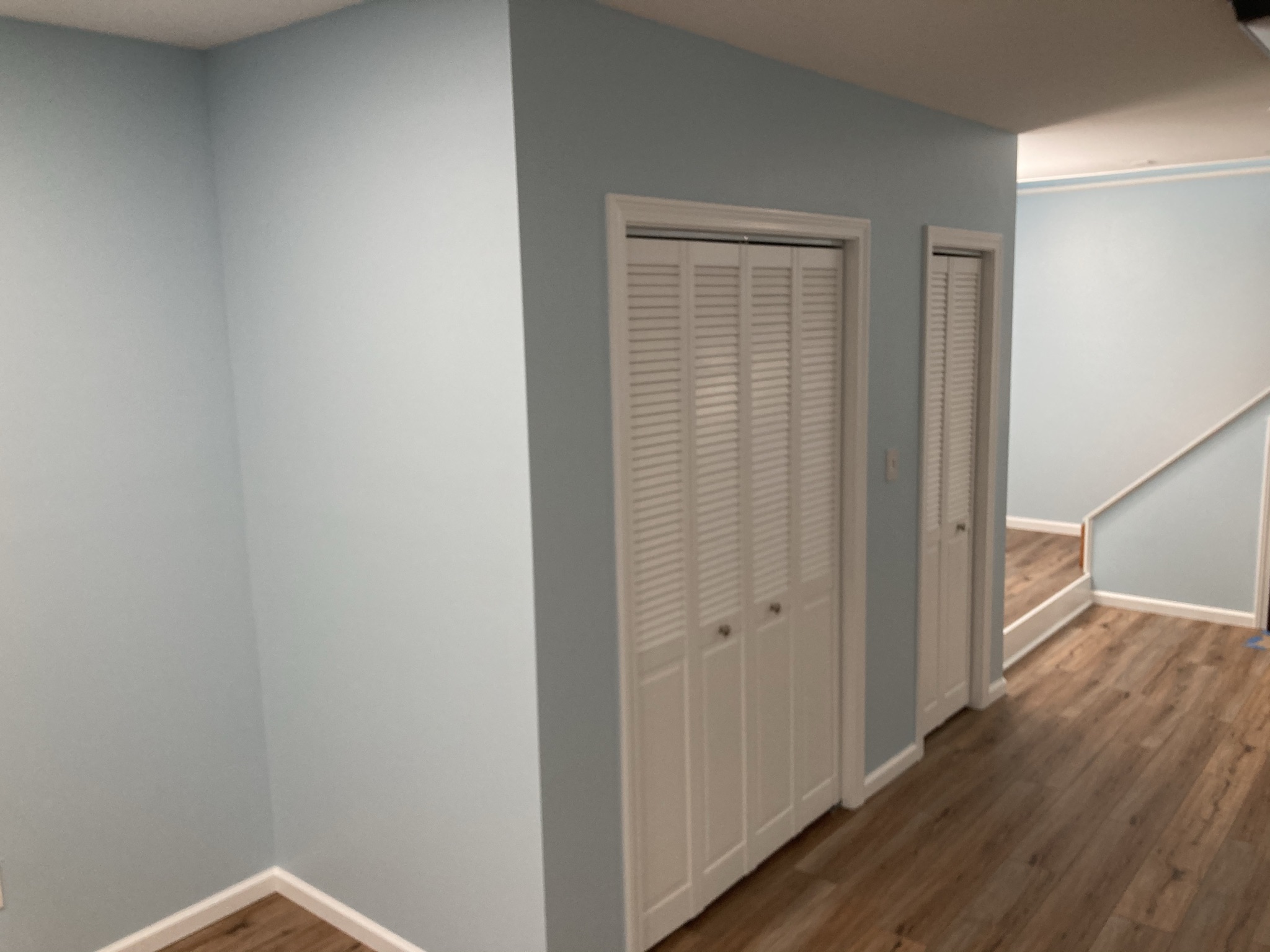 Finished basement landing with new flooring and a closet at the top of the stairs